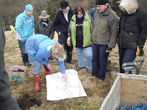 Photograph of community members looking at the orchard plan during the planting day